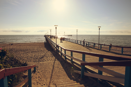Sea bridge with people at sunset. Pedestrian bridge at the Baltic sea in Palanga. Toned.の写真素材