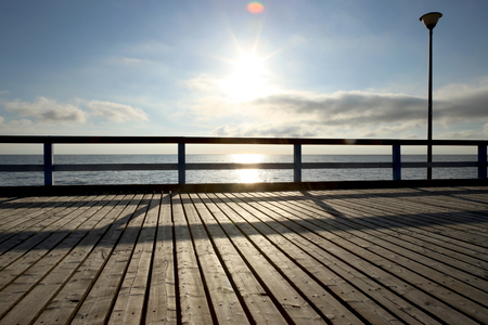 Wooden sea bridge at sunset. Empty pedestrian bridge over the sea in the evening.の写真素材