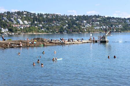 Oslo, Norway - July 22, 2018: Beach in Oslo Fjord. Beach is located on Ulvoya island of the inner Oslofjord, just east of the city center. People relax sunbathing and swimming, jumping from the trampoline.のeditorial素材
