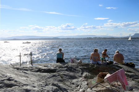 Oslo, Norway - July 24, 2018: Sunbathing people on rocky coast in Oslo Fjord. Scandinavian beach  in the inner Oslo Fjord.のeditorial素材