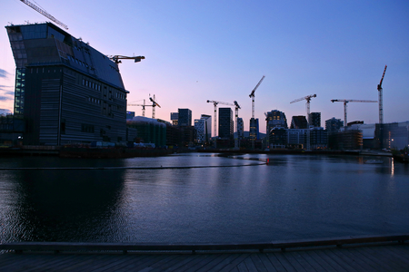 Background of silhouette skyscrapers and cranes under construction. Industrial city landscape at night, Bjorvika, Oslo, Norway.の写真素材