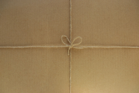 Tied string on cardboard background. Paper box tied with linen twine or rope.の写真素材