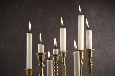 Burning candles in vintage metal candlesticks against dark stone background.
の写真素材
