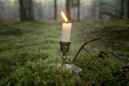 Single candle burning in forest. Burning candle in vintage candlestick outdoor.の写真素材