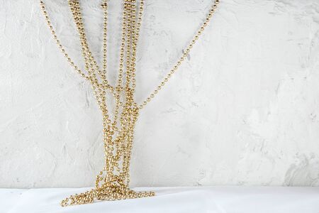 Golden Christmas garland on grunge wall with copy space. White plaster wall background with Christmas or New Year decoration.の写真素材