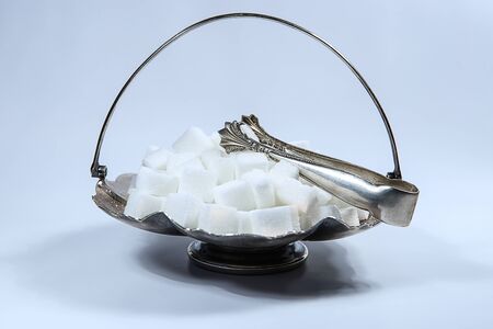 Sugar cubes in metal vintage sugar  bowl with sugar tongs.の写真素材