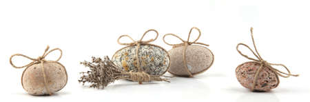 Sea smooth oval pebbles with bow and dried grasses isolated on white background. Round pebble stone...