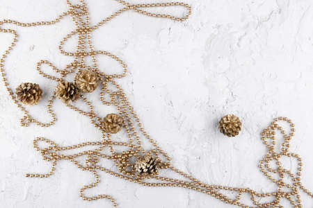 Christmas garland and golden cones on white concrete background., top view  Golden christmas...