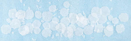 White round plastic foam sheet pieces on blue background. Winter snowfall concept. Torn foam...