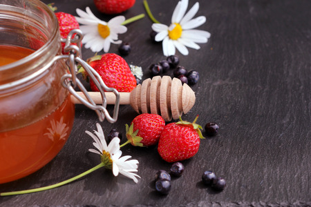 Honey glass,wooden dipper,berries on dark backgroundの写真素材