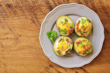 Avocado Egg Boats with bacon on wooden table. Top view.の写真素材