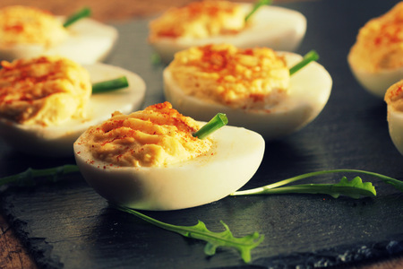 deviled eggs with red pepper on black background