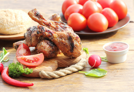 Grilled chicken legs with vegetables on cutting board.の写真素材