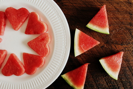 Fresh sliced watermelon on wooden background. Slices form of heartの写真素材