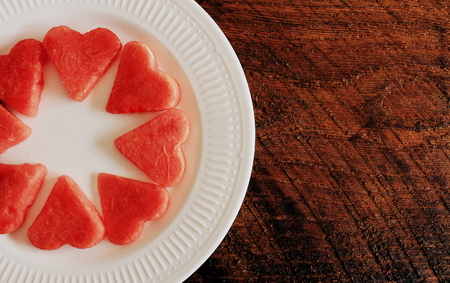 Fresh sliced watermelon on wooden background. Slices form of heartの写真素材