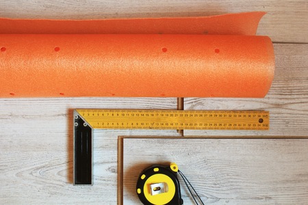 Laminate floor planks and tools on wooden background.
