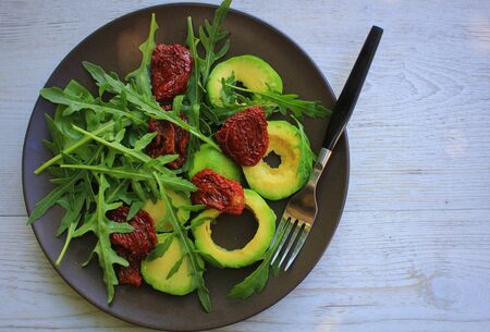 Healthy fitness salad with arugula, avocado and dry tomatoes. Vegetarian nutritious salad. Keto diet. Keto lunch idea recipe.の写真素材
