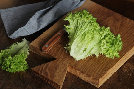 Healthy eating concept. Raw green organic lettuce ready to chop on cutting board with knife.