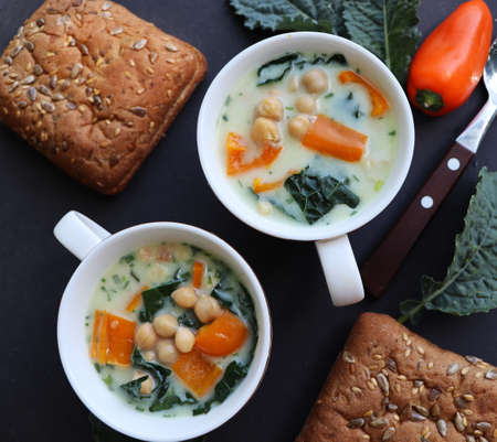 White soup of chickpeas, kale, pepper and potatoes in a bowl on the dark table. Top view .の写真素材