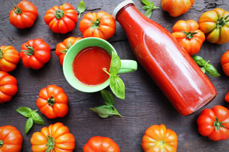 Flat lay composition with bottle of freshness juices on dark wooden background with red tomatoes and basil leaves .の写真素材