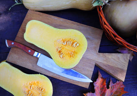 op view of butternut squash with seeds on rustic wooden tray. Pumpkin pieces, harvest, fall. Dark brown background. Cooking in autumn. Healthy food.の写真素材