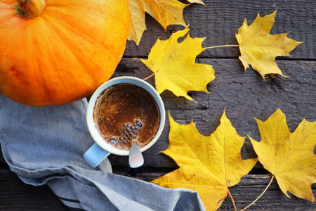 Autumn background. Blurred autumn leaves and pumpkin background with hot cup of coffeeの写真素材