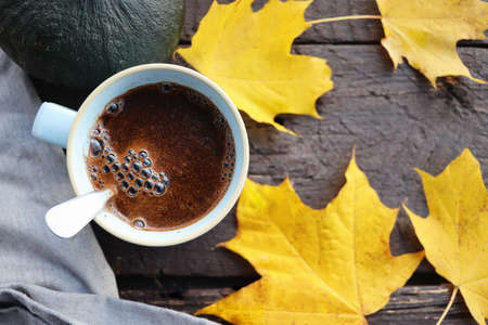 Autumn background. Blurred autumn leaves and pumpkin background with hot cup of coffee .の写真素材