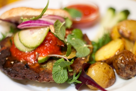 Delicious vegan burger with chickpea patty, pickled cucumbers, onion, ketchup, grilled red peppers,...