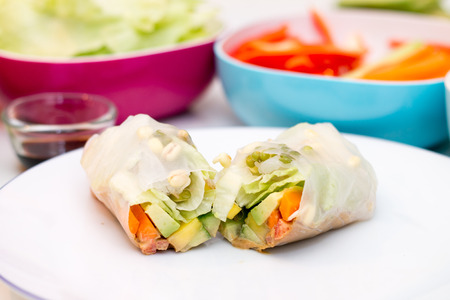 Fresh spring roll with vegetable filling on white plate against vibrant 