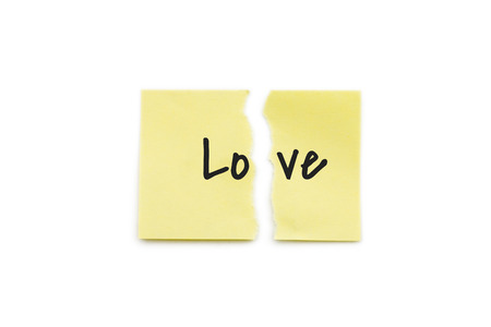Yellow paper note torn in two with the word love, isolated on white background