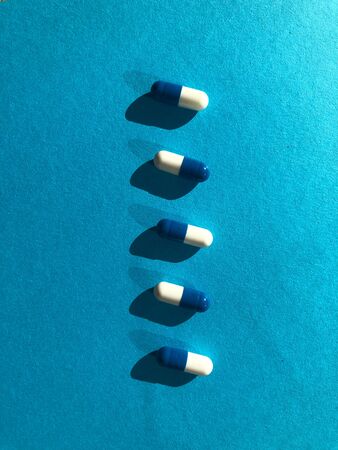 Blue and white pills on blue background.の写真素材