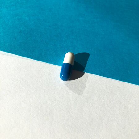 Blue and white pills on blue background.の写真素材
