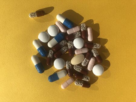 A lot of colorful pills on yellow background. Healthcare concept.
