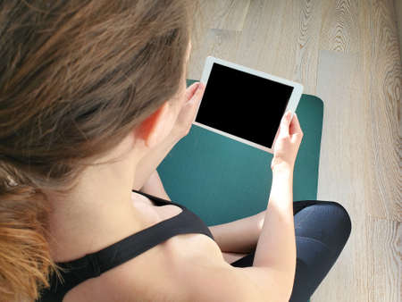 Beautiful young woman doing yoga on floor at home, online training.