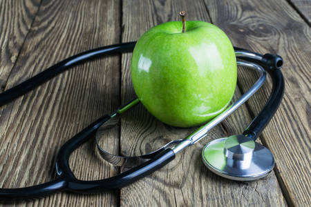 Stethoscope and green apple on a wooden background.の写真素材