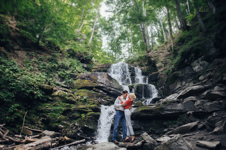 loving couple near a waterfall in forest.の写真素材