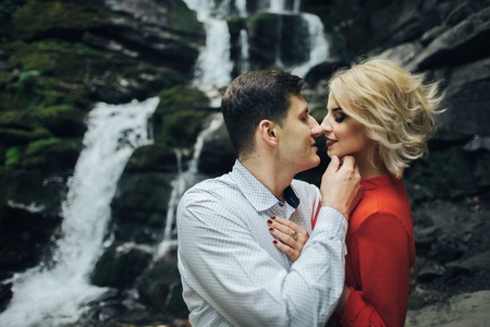 loving couple near a waterfall in forest.の写真素材