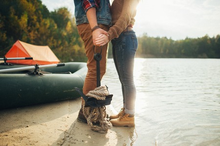 A loving couple stand on the bank of a mountain river, embracingの写真素材