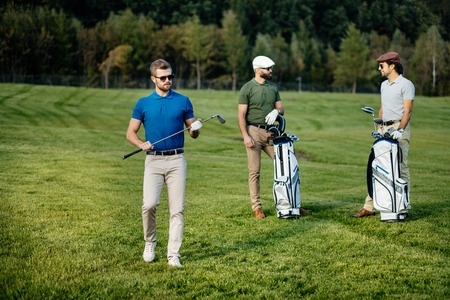 Golf player walking and carrying bag on course during summer gamの写真素材