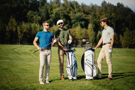 Golf player walking and carrying bag on course during summer gamの写真素材