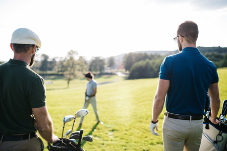 Golf player walking and carrying bag on course during summer gamの写真素材