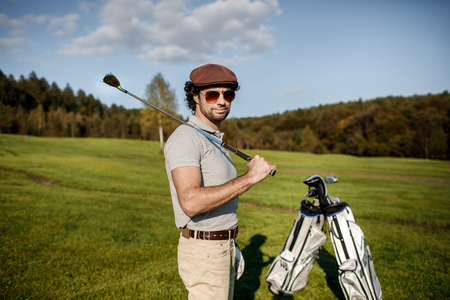 Full length view of man in cap holding golf club and hitting balの写真素材