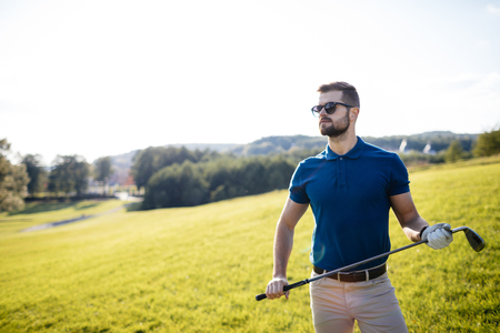 Full length view of man in cap holding golf club and hitting balの写真素材