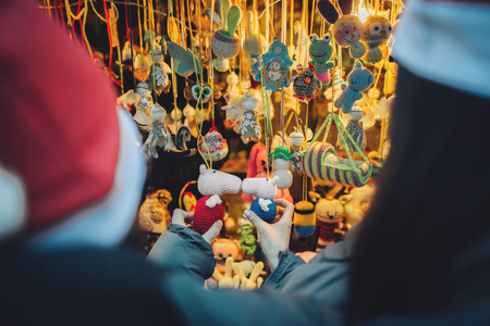 Couple in knitted clothes hugging outside, choosing a souvenirsの写真素材