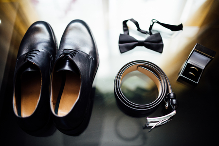 The groom's accessories. Leather shoes on a stone background with a bow tie and cufflinks on shoes of patent leather. Top view , bokeh.の写真素材