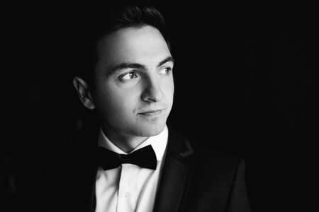 stylish groom smiling, portrait at the window while getting readの写真素材
