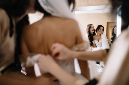 happy stylish gorgeous blonde bride with bridesmaids on the backの写真素材