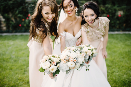 Laughing bride and bridesmaids tell funny stories standing on foの写真素材