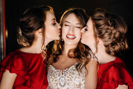 Beautiful bride and bridesmaids posing near window, wedding preparationの写真素材
