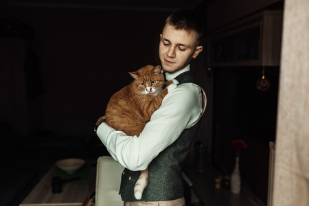 Cat hold by a groom while  preparing for wedding ceremonyの写真素材